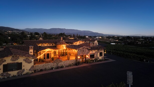 A building with a stone facade, multiple windows, and a signpost in the foreground. - Sleeps 8, 2 Homes | Vineyard Views, Patios in Temecula Wine Trail (Temecula)