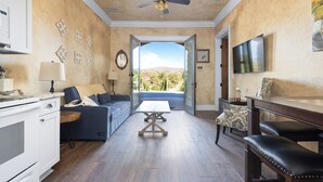 A spacious living area with a sofa, coffee table, and a dining table with chairs. A ceiling fan is visible, and there is a view through an open door to the outdoors. - Sleeps 8, 2 Homes | Vineyard Views, Patios in Temecula Wine Trail (Temecula)