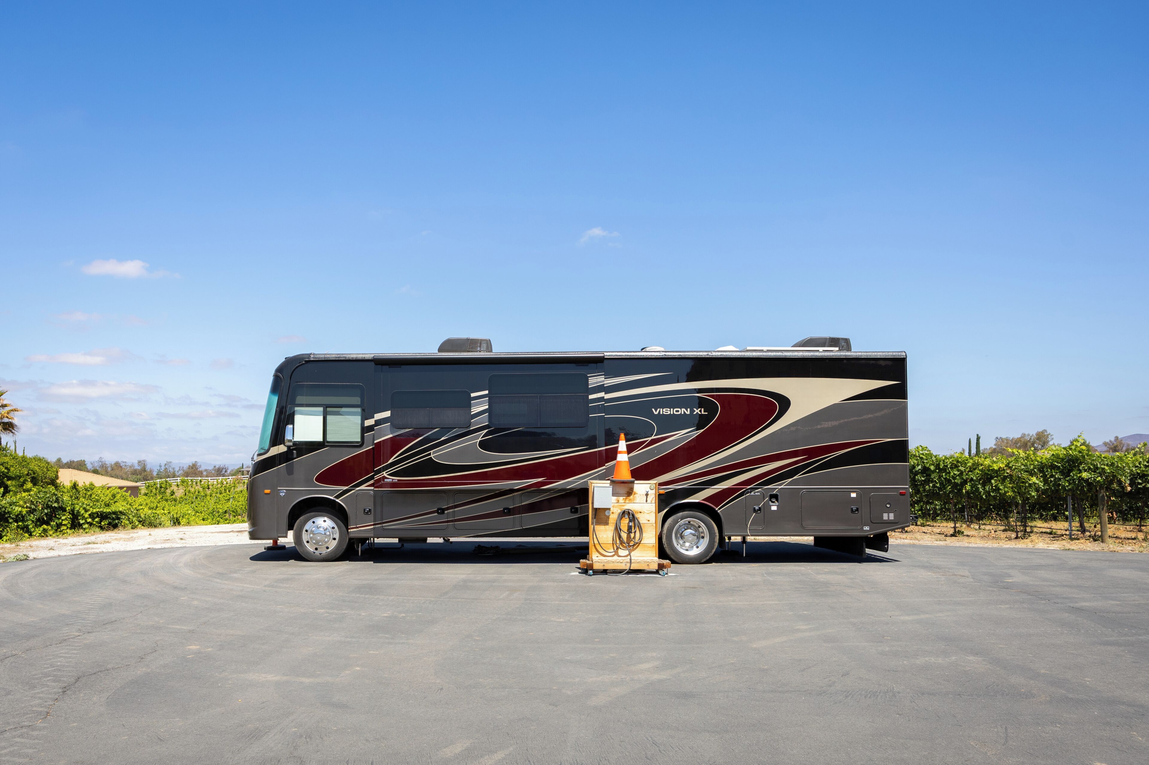 A large RV parked in a lot with a clear sky.