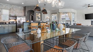 A modern kitchen with a central island, stainless steel appliances, and a dining area with wire chairs. - Designer Desert Oasis w/ Pool, Hot Tub, Outdoor Lounge | The Riley by AvantStay (Indio)
