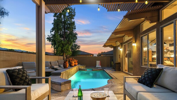 A poolside area with outdoor seating, a hot tub, and a view of the sunset. - Designer Desert Oasis w/ Pool, Hot Tub, Outdoor Lounge | The Riley by AvantStay (Indio)