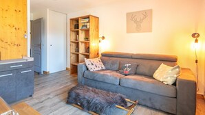 Un salon chaleureux avec un canapé gris, une bibliothèque en bois et un tapis en fourrure.