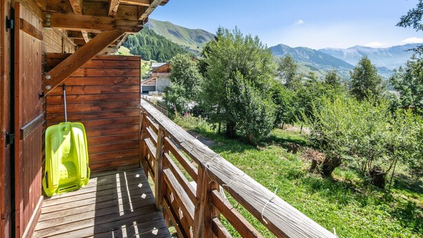 Un balcon en bois offrant une vue sur un paysage montagneux.