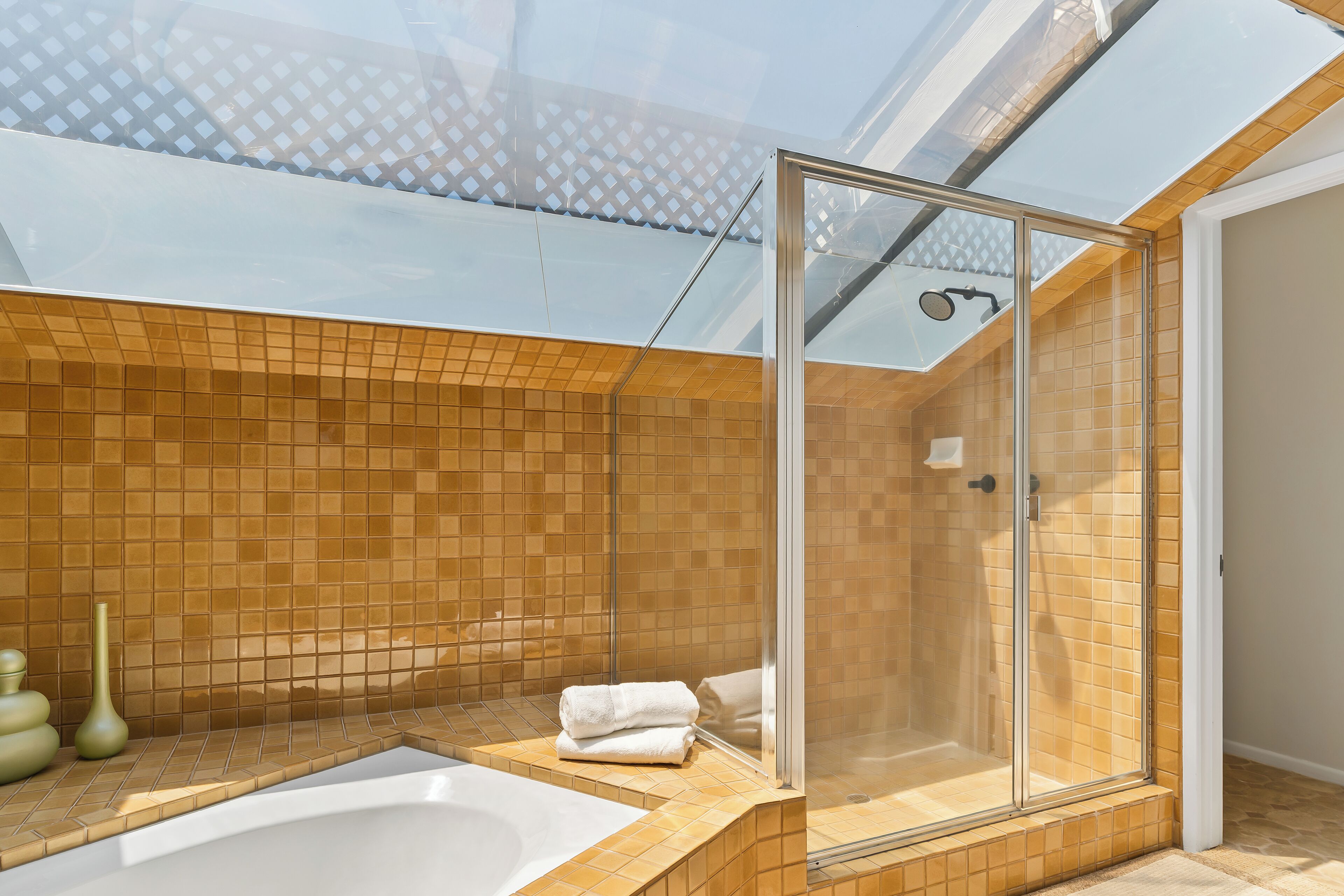 Un baño moderno con ducha envuelta en vidrio, una bañera y suelo de baldosas.