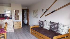 A room with a wooden bed, a wooden chair, a wooden dresser, and a kitchen area with a microwave. - Mountain Apartment in Saint-Sorlin (Saint-Sorlin-d´Arves)