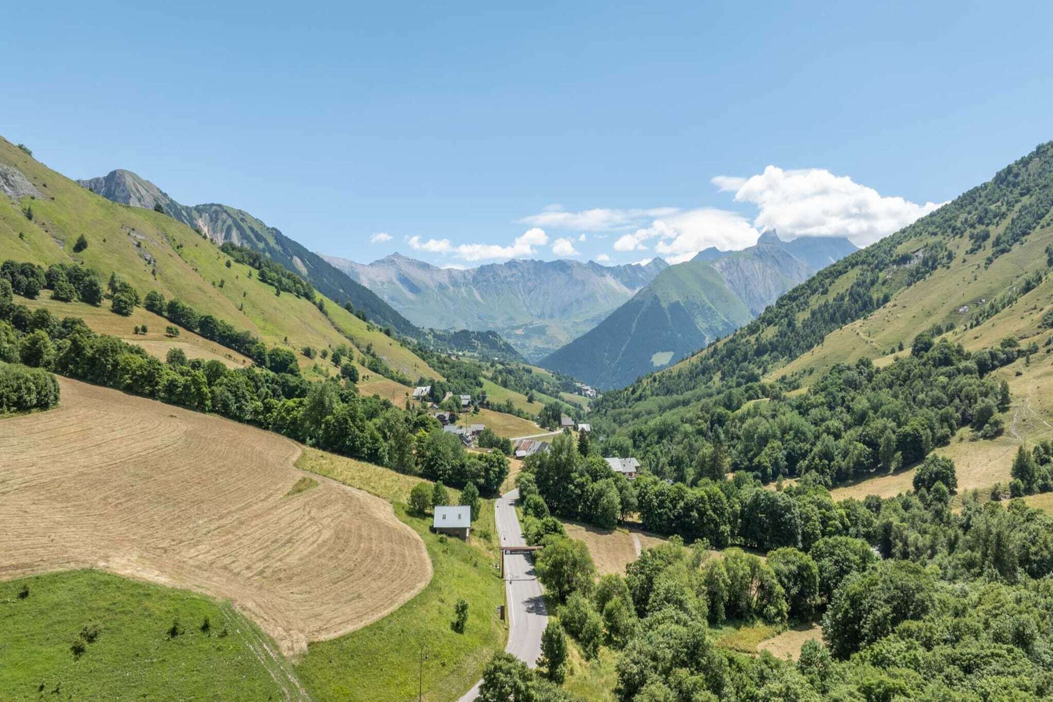 A rural landscape with a valley, houses, and mountains.