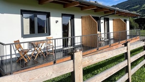 Een modern gebouw met een balkon, een houten terras en uitzicht op de bergen.
