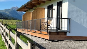 Een moderne chalets met een houten balkon, grote ramen en uitzicht op bergen.