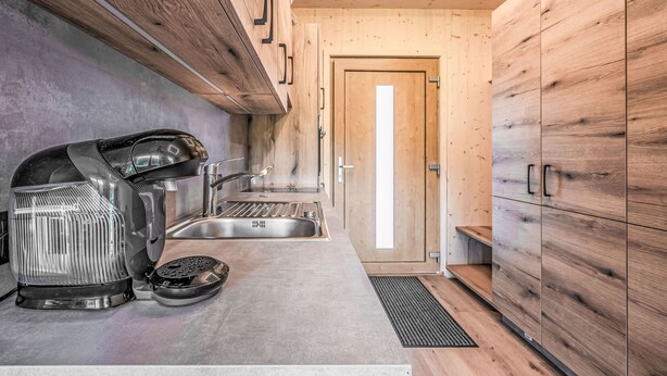 Une cuisine moderne avec des meubles en bois, un évier en acier inoxydable et une machine à café.