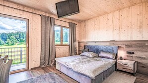 Une chambre à coucher avec un lit, une télévision, une table de chevet et une fenêtre avec des rideaux.