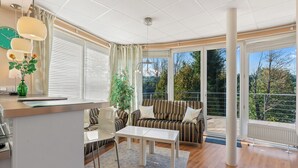 A modern living room with a sofa, a dining table, and a kitchen area.