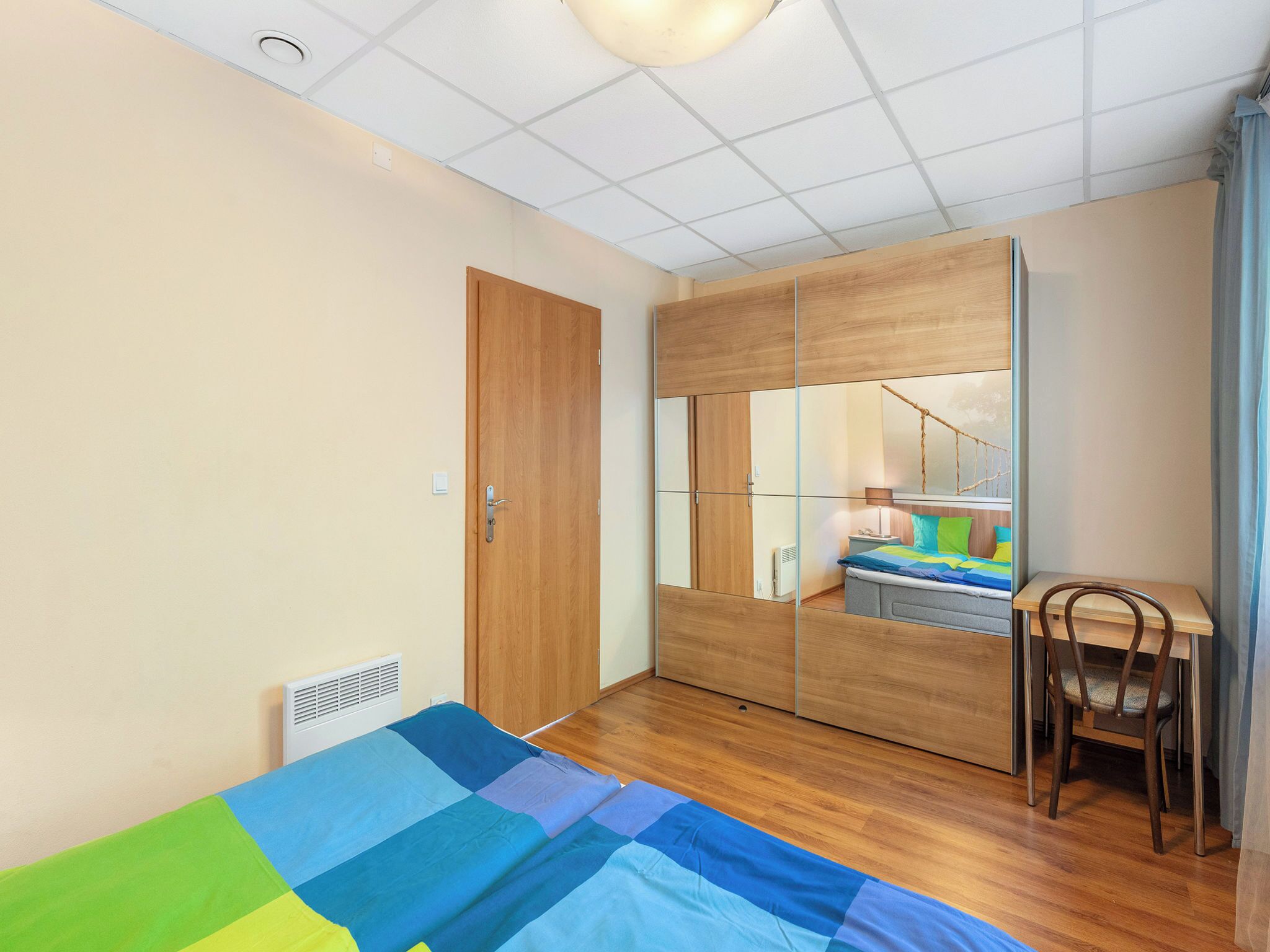 Une chambre à coucher avec un lit, une armoire en bois, un bureau et une chaise.