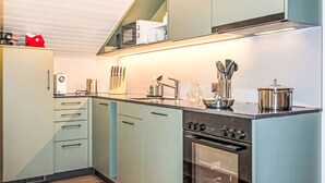 A modern kitchen with a built-in oven, stainless steel appliances, and a range hood. - Juliana by Interhome (Zermatt)