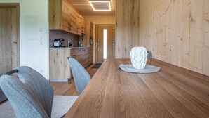 Un interior de madera con una mesa de comedor, sillas y una zona de cocina.