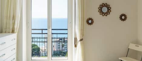 A room with a large sliding glass door leading to a balcony with a city view.