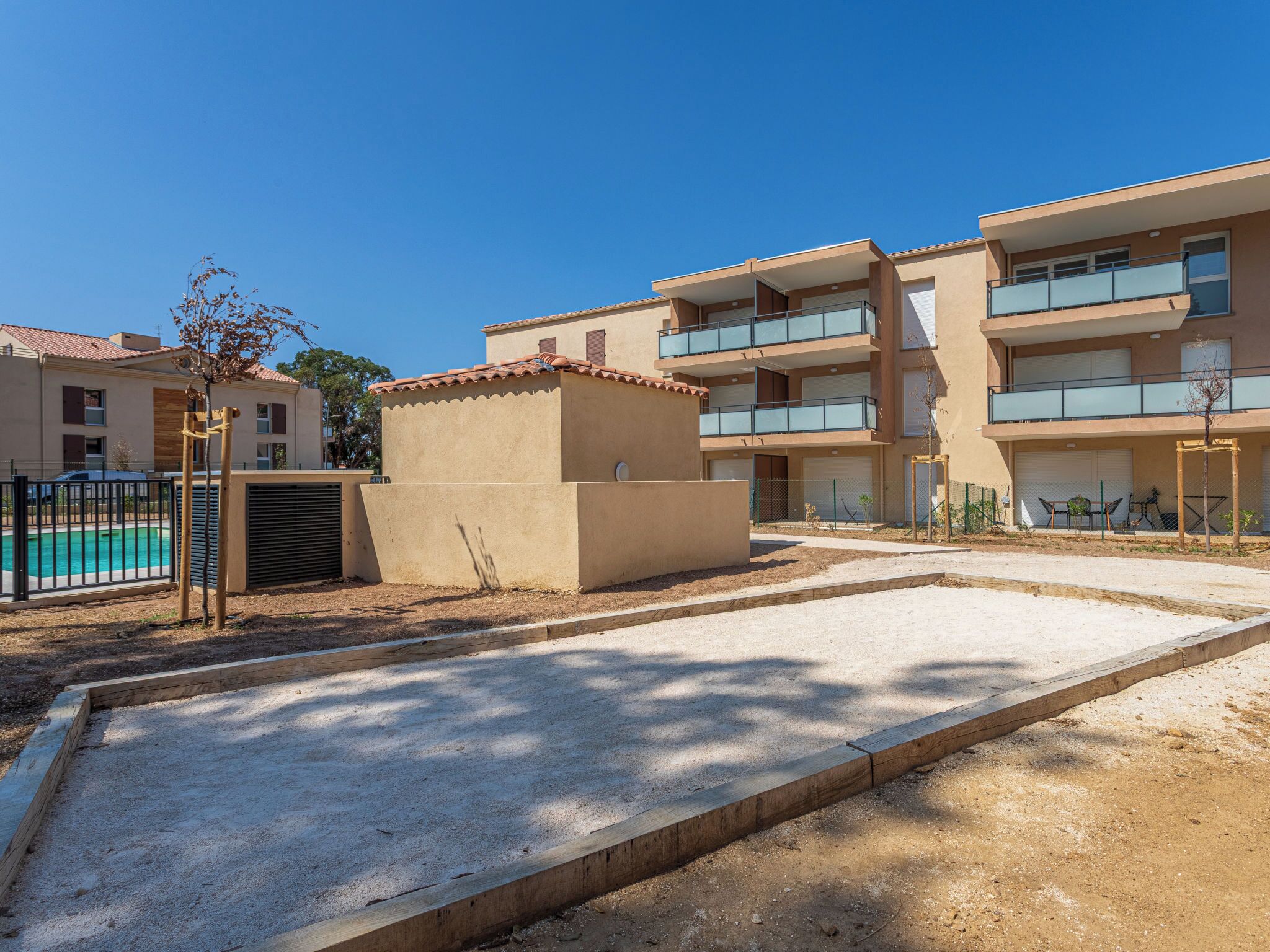 A residential building with multiple balconies, a swimming pool, and a small garden area.