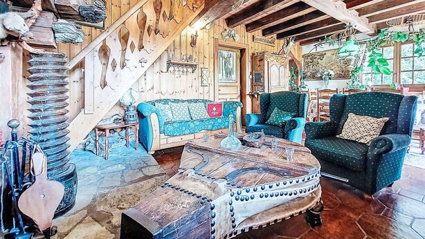 A rustic cabin interior with a wooden staircase, a blue patterned sofa, a green armchair, and a coffee table with a woven cover. - Chalet le Prarion by Interhome (Saint Gervais)