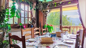 A dining area with a table set for six, surrounded by wooden chairs, a chandelier, and potted plants. - Chalet le Prarion by Interhome (Saint Gervais)