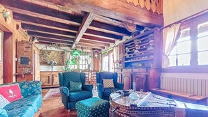 A cozy room with wooden beams, a sofa, armchairs, and a table with a vase. - Chalet le Prarion by Interhome (Saint Gervais)