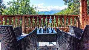 A wooden deck with wicker chairs and a table, overlooking a scenic landscape with trees and mountains. - Chalet le Prarion by Interhome (Saint Gervais)