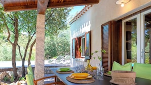 An outdoor dining area with a table set for four, surrounded by wooden chairs.