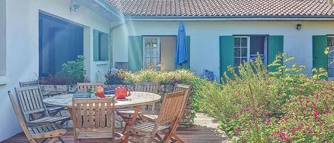 A patio with a round table and chairs, surrounded by potted plants and a small garden.