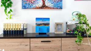 A wooden desk with a blue book, a framed picture, and a plant.