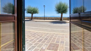 Un sendero pavimentado que conduce a un muro de piedra con dos árboles y un farol.