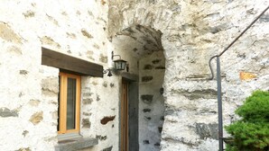 A stone building with a wooden door and window, a stone staircase, and a metal lamp post. - Rustico Emilio by Interhome (Roveredo)