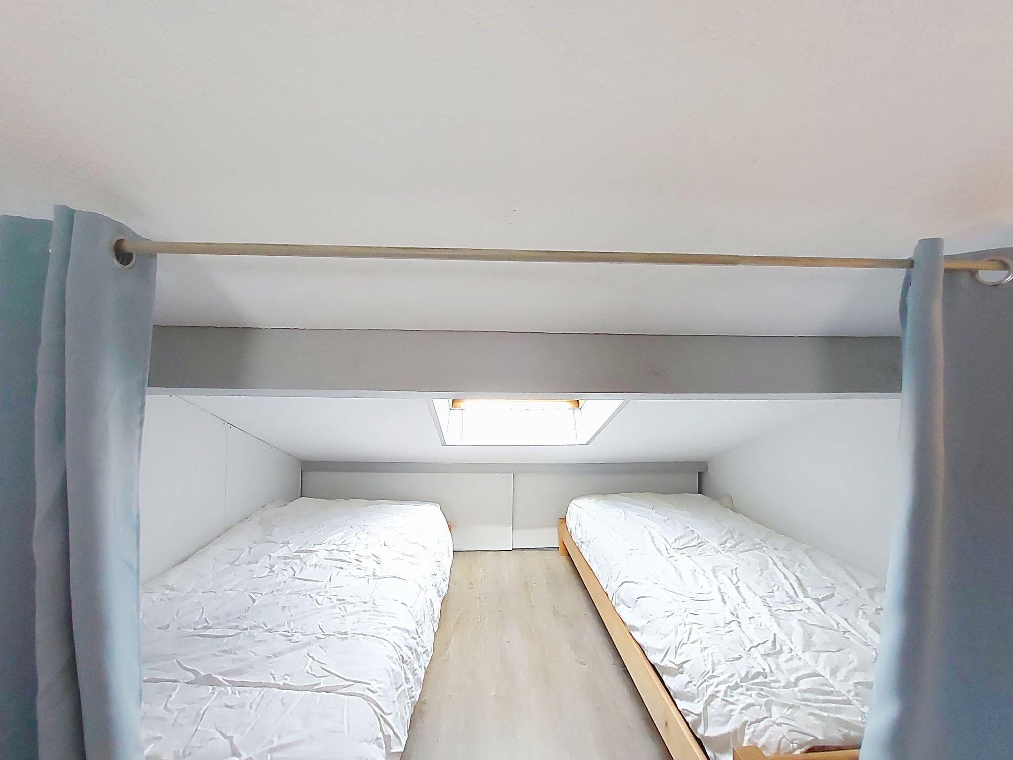 Una habitación pequeña y sencilla con dos camas, un tragaluz y un diseño funcional.