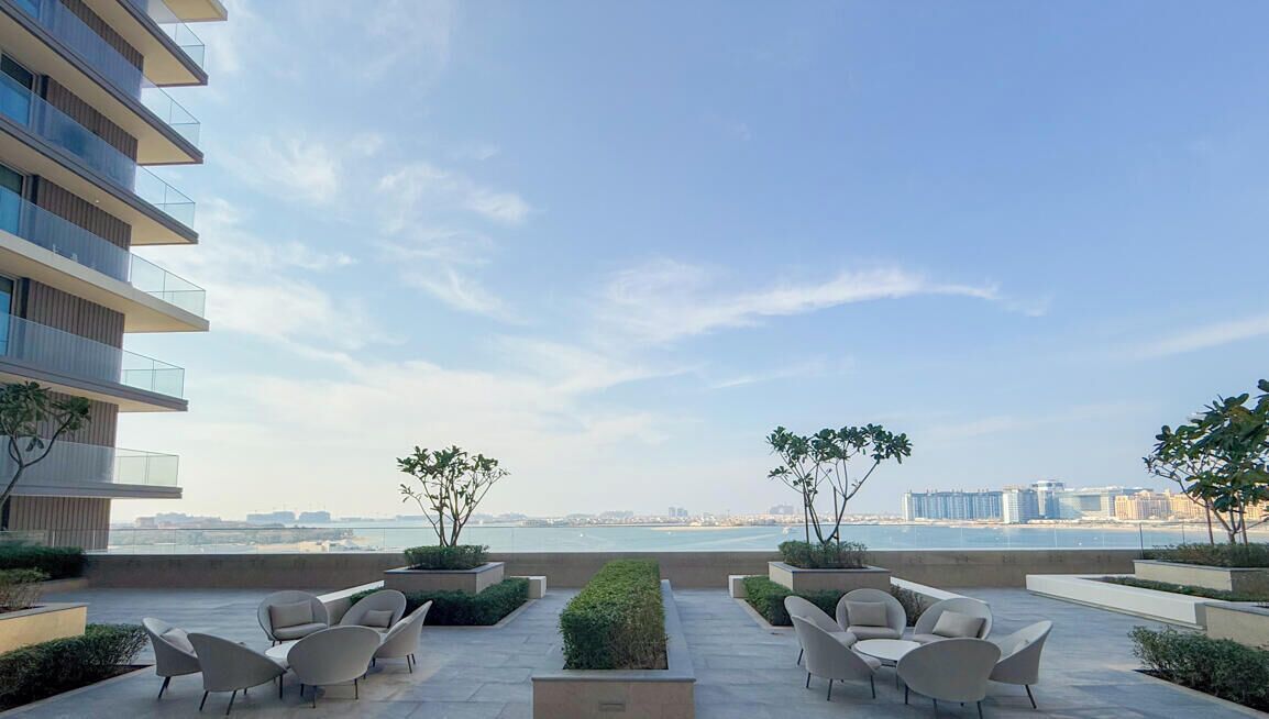 A rooftop patio with outdoor seating and a view of the city skyline.