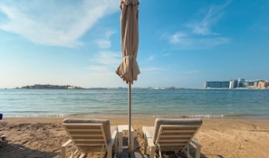 Une plage avec deux chaises longues et un parasol.
