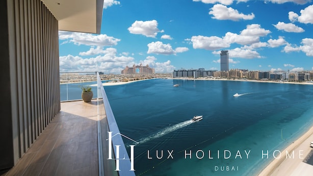 Een luxueus balkon met uitzicht op de kustlijn van Dubai, inclusief een jachthaven en stadsbeeld.