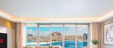 A modern living room with a large window offering a cityscape view, a flat-screen TV, and a comfortable seating area.