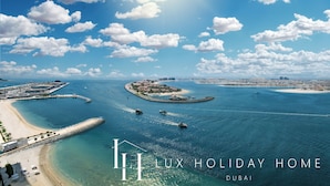 Luchtbeeld van een kustgebied met een strand, water en een klein eiland met gebouwen.
