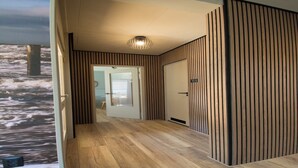 A hallway with wooden flooring and vertical paneling on the walls.