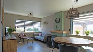 A modern living room with a sofa, a round wooden table, and a built-in wood stove.