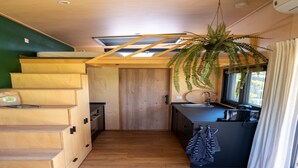 Een kleine keuken met houten kastjes, een spoelbak en een raam met gordijnen.