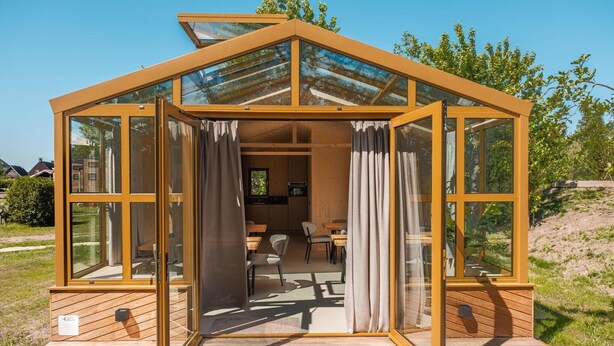 Een moderne, open structuur van hout met grote glasramen en een houten terras.