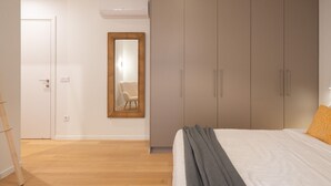 A bedroom with a bed, a wardrobe, a mirror, and a door. - LIV Athinum 1 - Luxury Apartment 4C (Athens)