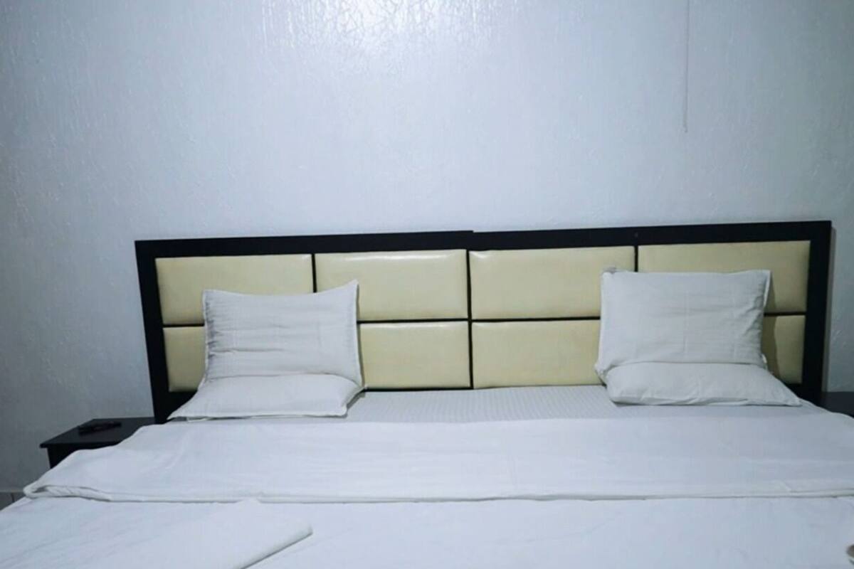 A hotel room with a bed, two bedside tables, and a plain wall.