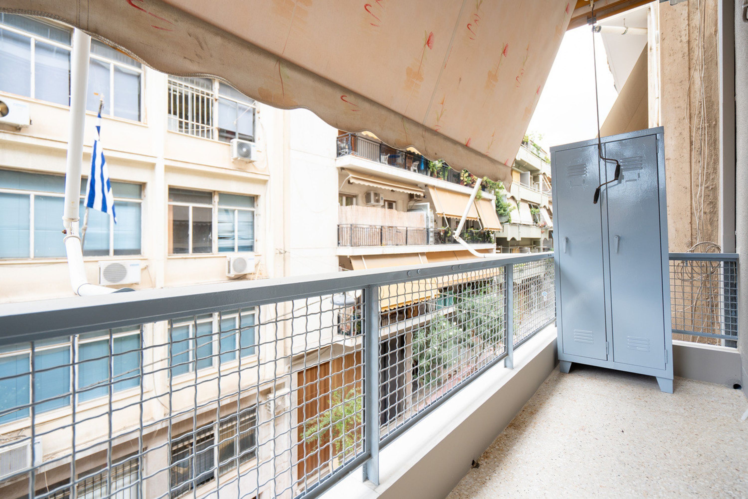 Ein Balkon mit Metallgeländer, einem blauen Verteilerkasten und einem grauen Metallschrank.