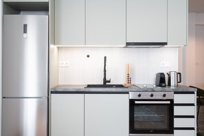 A modern kitchen with stainless steel appliances, a built-in oven, and a black faucet. - LIV - Premium Pagrati Apartment With View (Athens)