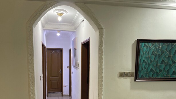 Un pasillo con suelo de baldosas, una obra de arte enmarcada en la pared y una puerta al final.
