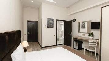 A modern bedroom with a large bed, a desk, a chair, and a mirror.