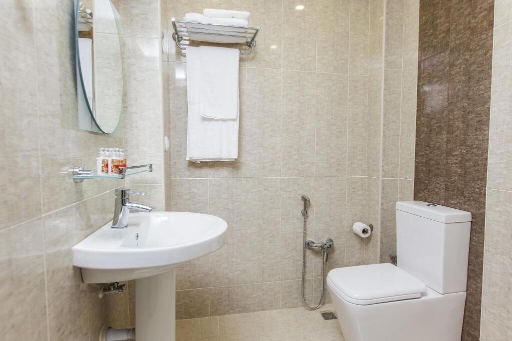 A modern bathroom with a white sink, a toilet, and a shower.