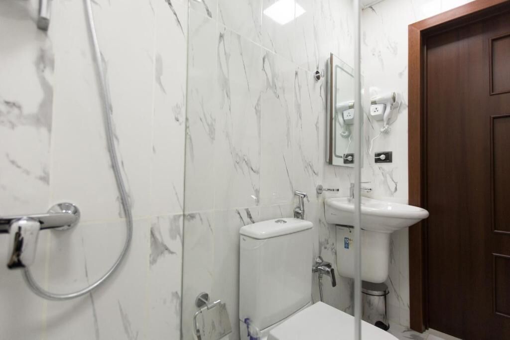 Une salle de bain avec des toilettes, un lavabo et une douche.