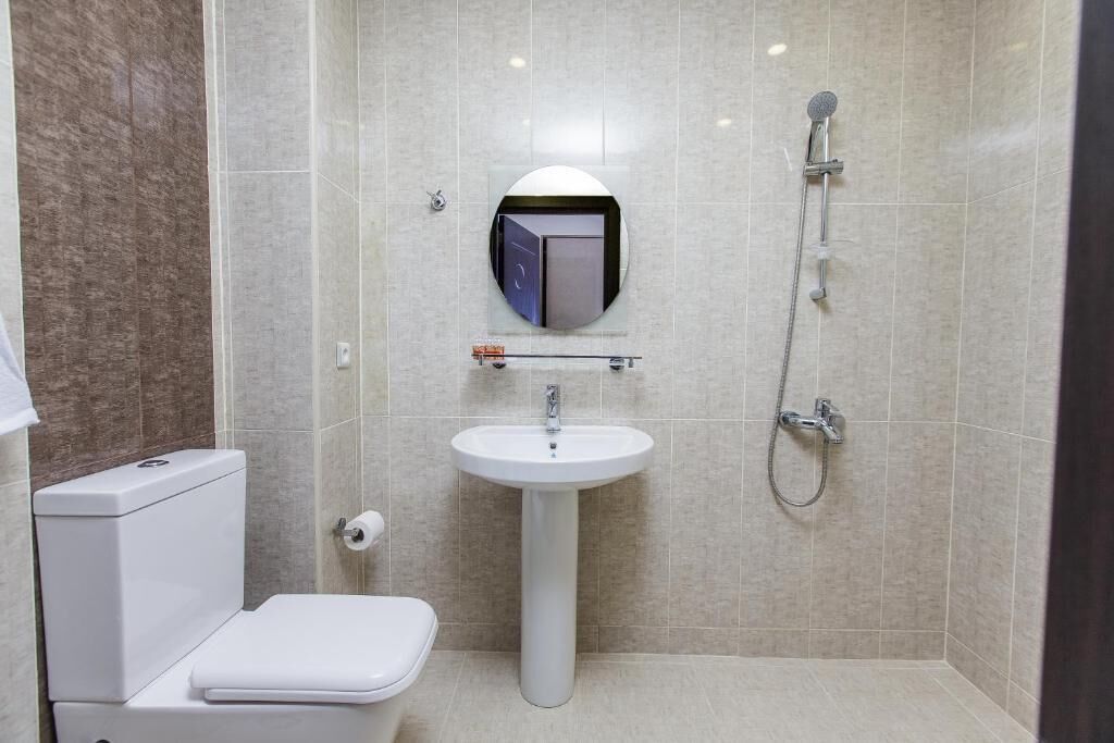 A compact bathroom with a toilet, sink, and shower.