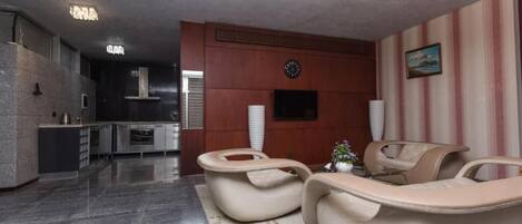 A modern kitchen with a built-in oven and a dining area with a beige sofa and a small table.