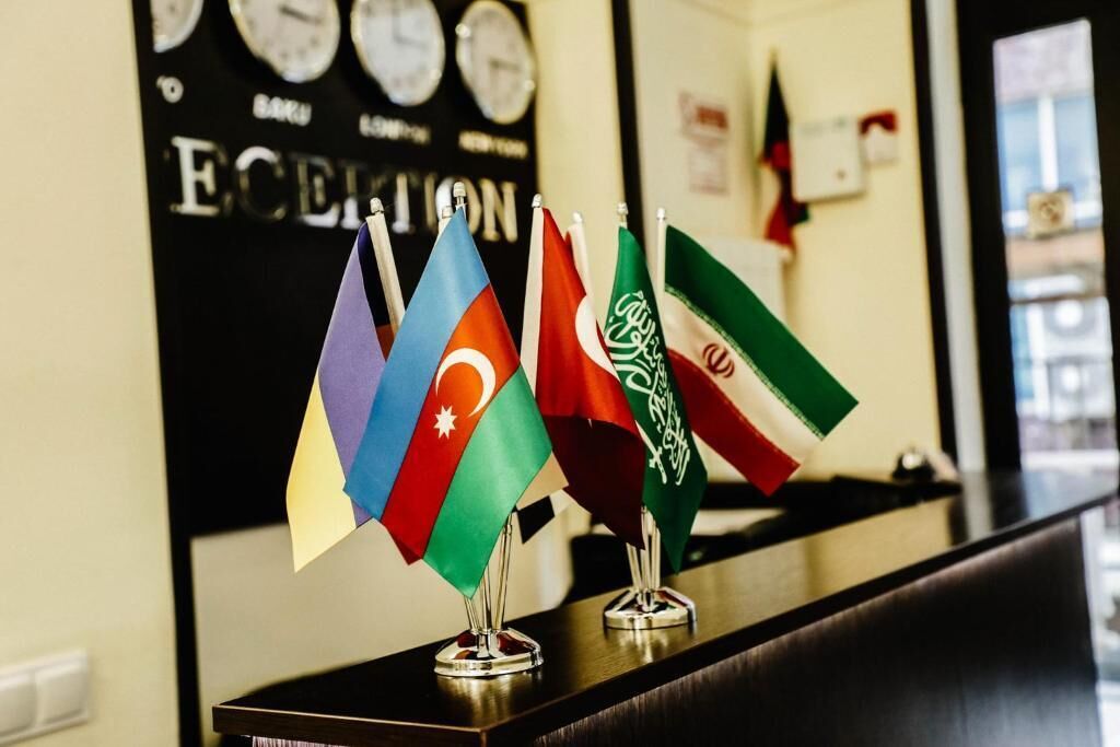A set of flags on a table in a room with a clock and a sign that reads "ECHEVION".